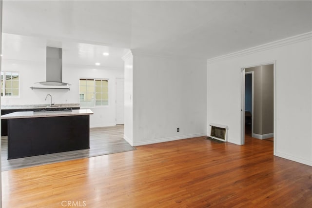 unfurnished living room with hardwood / wood-style flooring, ornamental molding, and sink