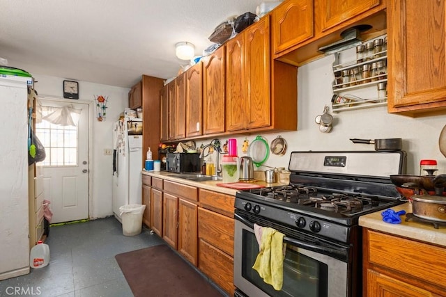 kitchen with sink, gas stove, and white refrigerator