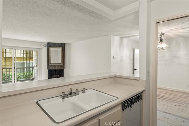 kitchen with dishwashing machine, sink, a fireplace, light hardwood / wood-style floors, and a textured ceiling