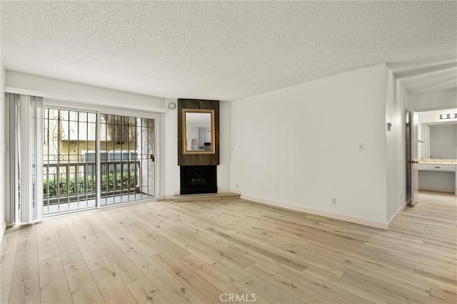 unfurnished living room with a large fireplace, light hardwood / wood-style flooring, and a textured ceiling