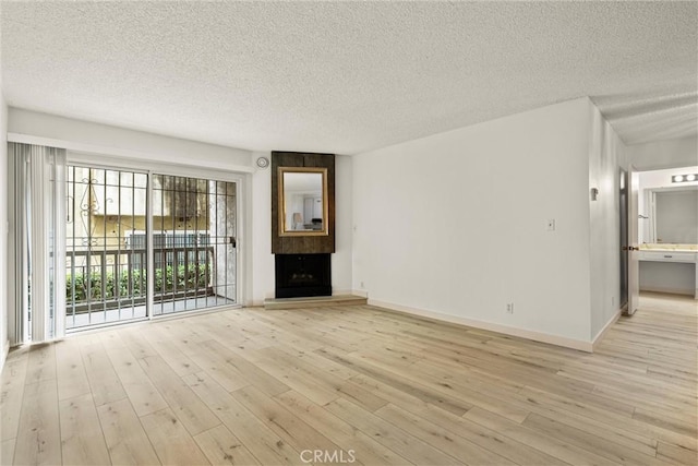 8740 Tuscany Ave Unit 109, Playa Del Rey, CA 90293 - unfurnished living room with a textured ceiling, light wood-style flooring, and a fireplace