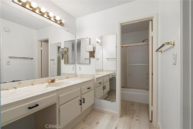 bathroom with vanity, a shower with shower door, hardwood / wood-style floors, and a textured ceiling