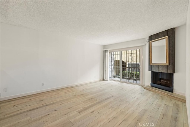 unfurnished living room featuring a fireplace, light hardwood / wood-style flooring, and a textured ceiling