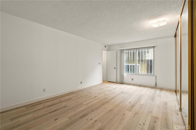 unfurnished room with a textured ceiling and light wood-type flooring