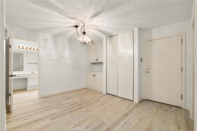 interior space featuring an inviting chandelier, light hardwood / wood-style floors, and a textured ceiling