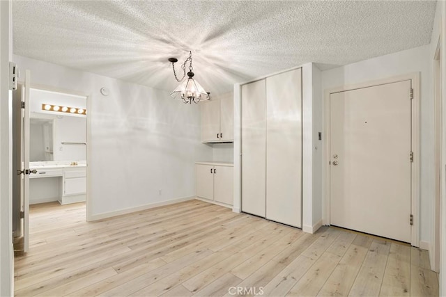 8740 Tuscany Ave Unit 109, Playa Del Rey, CA 90293 - unfurnished dining area featuring light wood-type flooring, a textured ceiling, and a chandelier