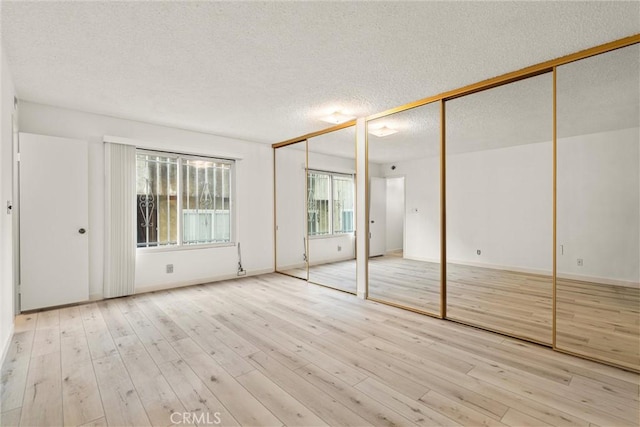 8740 Tuscany Ave Unit 109, Playa Del Rey, CA 90293 - unfurnished bedroom with multiple closets, a textured ceiling, wood finished floors, and baseboards