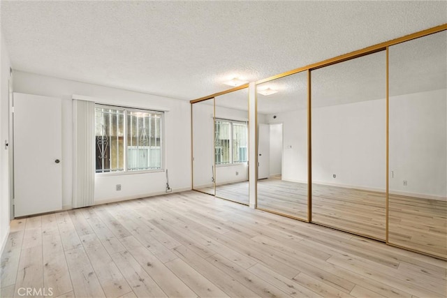 8740 Tuscany Ave Unit 109, Playa Del Rey, CA 90293 - unfurnished bedroom featuring two closets, a textured ceiling, and wood finished floors
