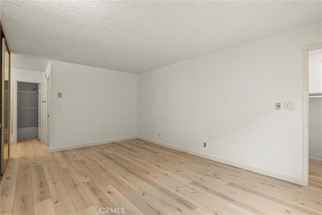 spare room with a textured ceiling and light wood-type flooring