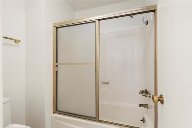 bathroom with bath / shower combo with glass door and toilet