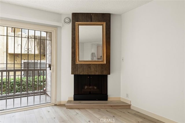 doorway to outside featuring a wealth of natural light, a textured ceiling, and light wood-type flooring