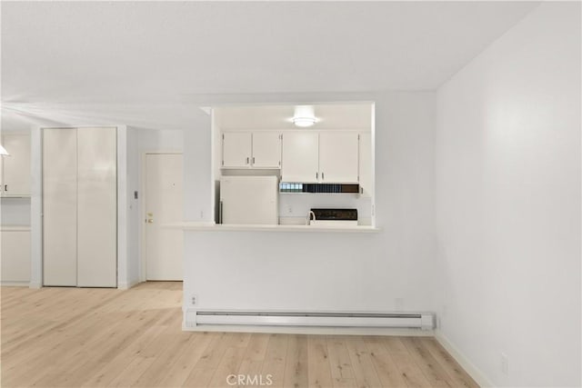 8740 Tuscany Ave Unit 109, Playa Del Rey, CA 90293 - kitchen with freestanding refrigerator, a baseboard heating unit, light wood-style flooring, and white cabinets