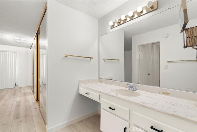 8740 Tuscany Ave Unit 109, Playa Del Rey, CA 90293 - bathroom featuring a textured ceiling, wood finished floors, vanity, and baseboards