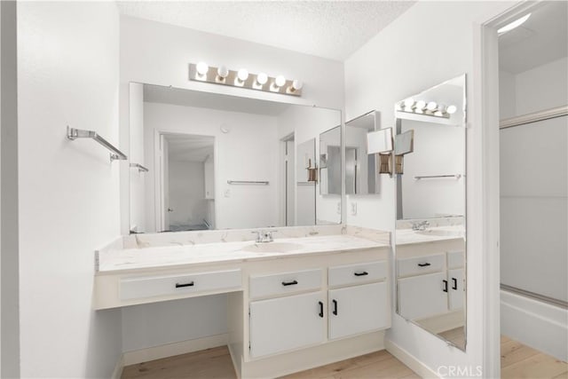 8740 Tuscany Ave Unit 109, Playa Del Rey, CA 90293 - bathroom featuring double vanity, wood finished floors, a shower with door, and a textured ceiling
