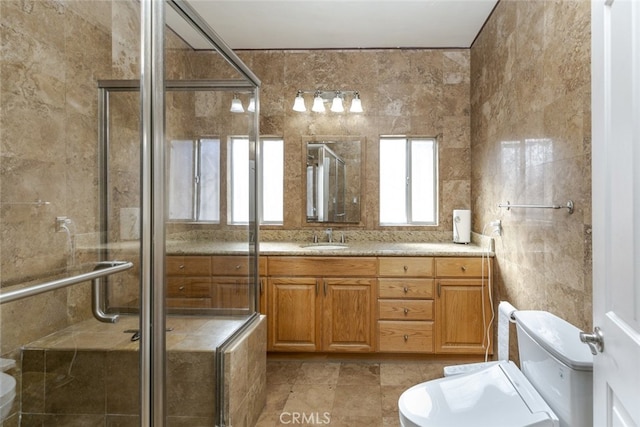 bathroom featuring walk in shower, vanity, toilet, and tile walls