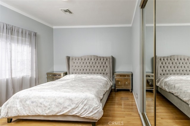 bedroom featuring hardwood / wood-style flooring, crown molding, and a closet