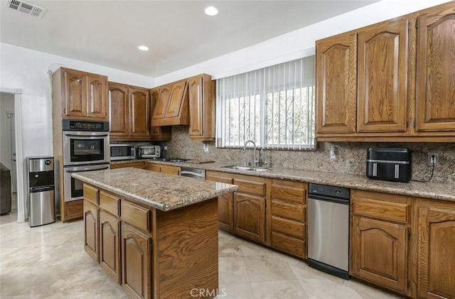 kitchen featuring sink, decorative backsplash, a center island, and appliances with stainless steel finishes