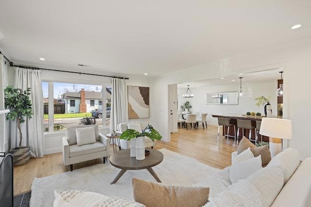 living room with crown molding, a healthy amount of sunlight, and light wood-type flooring