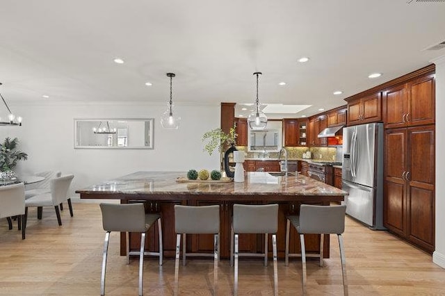 kitchen with a spacious island, a breakfast bar area, light stone counters, appliances with stainless steel finishes, and pendant lighting