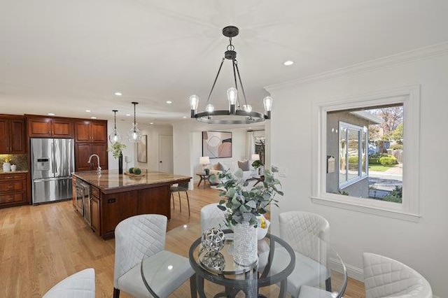 dining space featuring sink, light hardwood / wood-style flooring, and ornamental molding