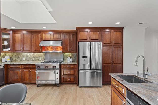 kitchen featuring sink, appliances with stainless steel finishes, light stone counters, tasteful backsplash, and light hardwood / wood-style floors