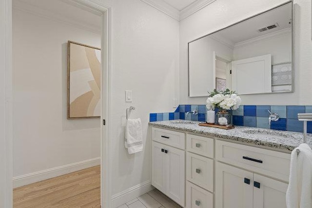 bathroom featuring ornamental molding, hardwood / wood-style floors, and vanity