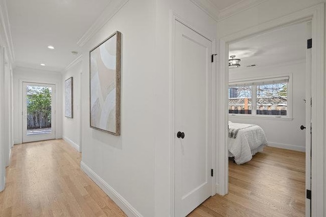 corridor with crown molding, plenty of natural light, and light wood-type flooring