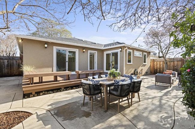 rear view of property featuring an outdoor living space, a deck, and a patio