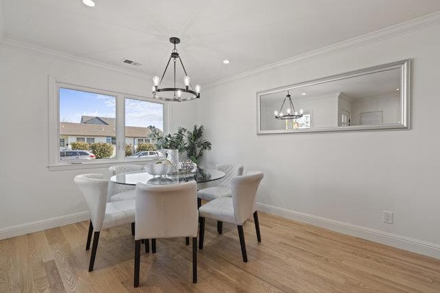 dining room featuring ornamental molding, light wood-type flooring, and a chandelier