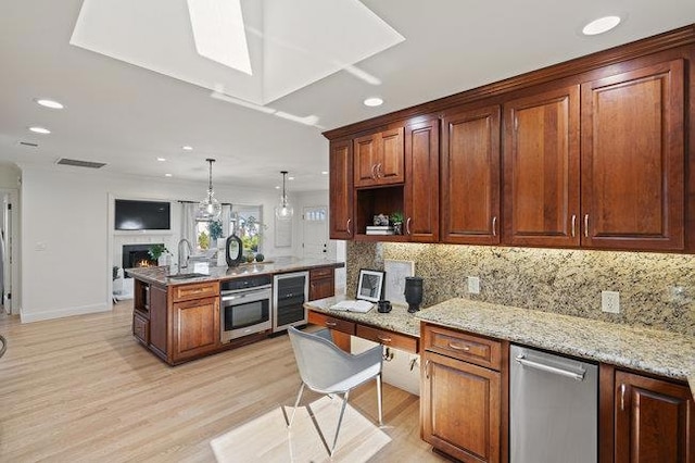 kitchen featuring sink, appliances with stainless steel finishes, hanging light fixtures, light stone counters, and tasteful backsplash