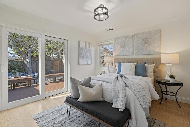 bedroom with crown molding, wood-type flooring, and access to exterior