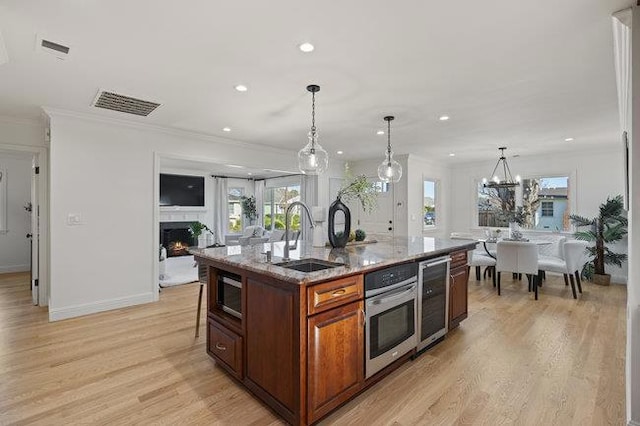 kitchen with sink, decorative light fixtures, stainless steel appliances, and a center island with sink