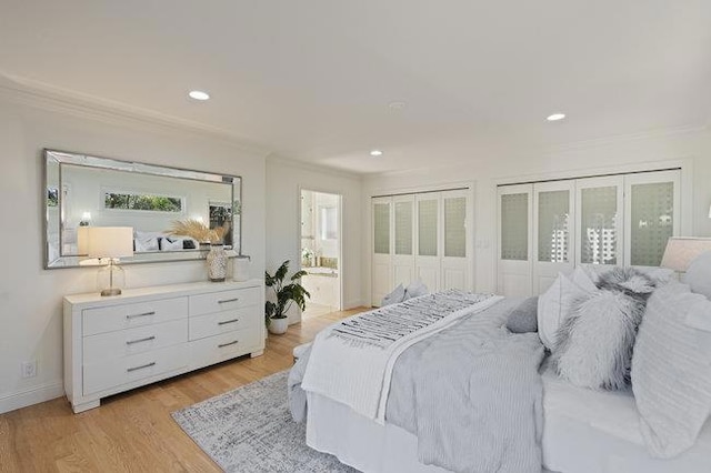 bedroom featuring ornamental molding, ensuite bathroom, and light hardwood / wood-style flooring