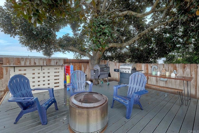 deck with grilling area and a fire pit