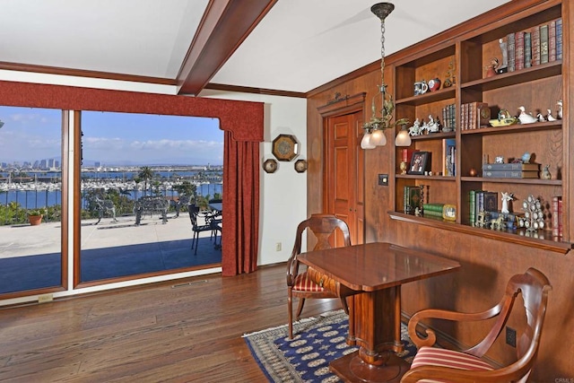 dining room featuring dark hardwood / wood-style flooring, ornamental molding, beamed ceiling, and a water view