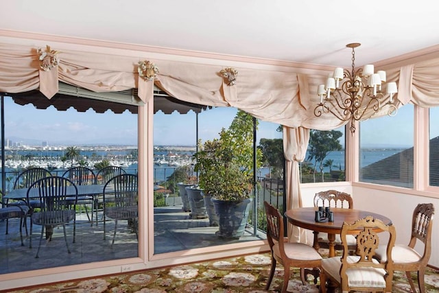 sunroom featuring a chandelier, a healthy amount of sunlight, and a water view