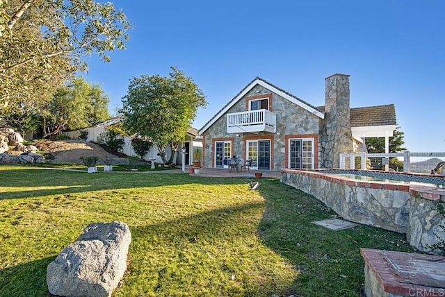 rear view of house featuring a balcony, a yard, and a patio