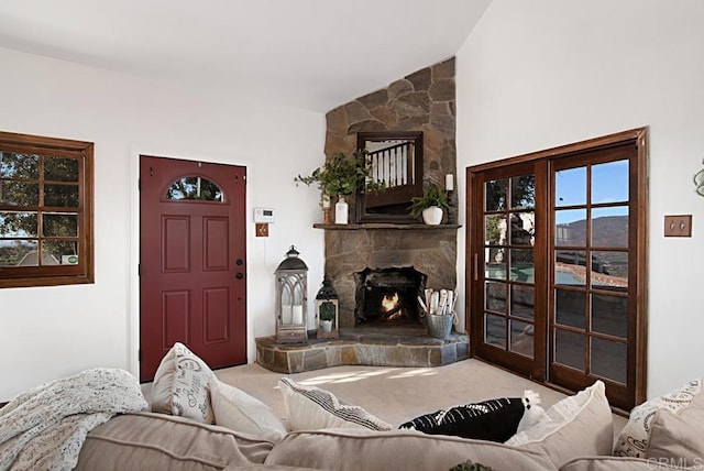 living room with lofted ceiling, a mountain view, a stone fireplace, and carpet floors