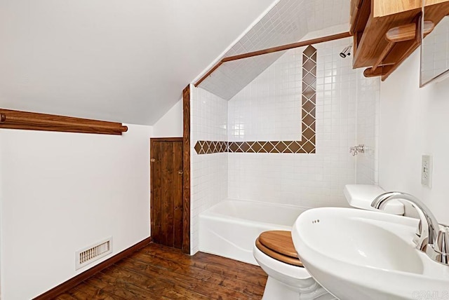 full bathroom featuring lofted ceiling, toilet, sink, tiled shower / bath combo, and hardwood / wood-style floors