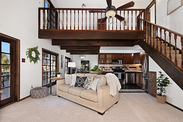 living room with ceiling fan, light colored carpet, and a high ceiling