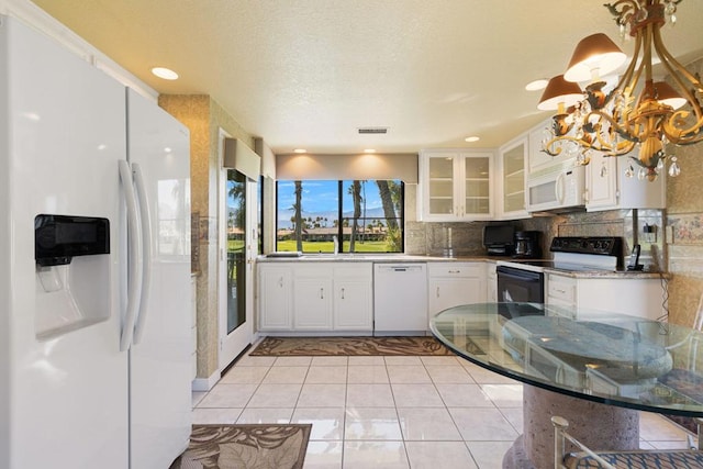 kitchen featuring white appliances, white cabinetry, tasteful backsplash, stone countertops, and a chandelier