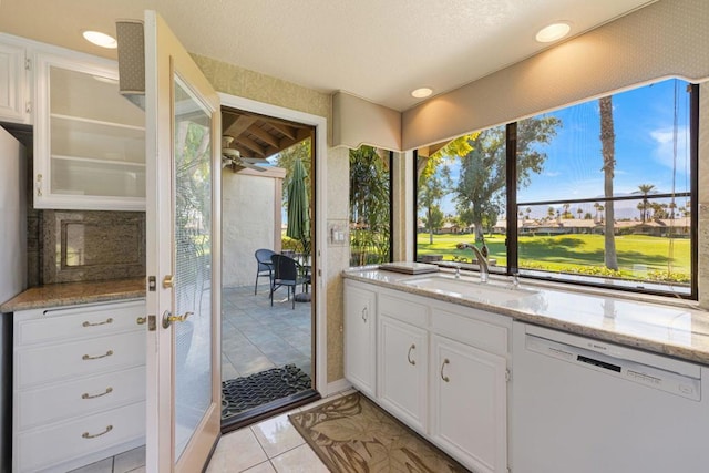 kitchen featuring sink, white cabinetry, light stone counters, white dishwasher, and ceiling fan