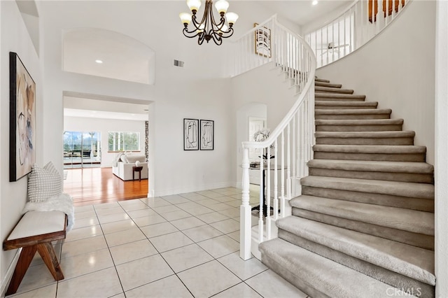 stairs featuring a high ceiling, a notable chandelier, and tile patterned floors