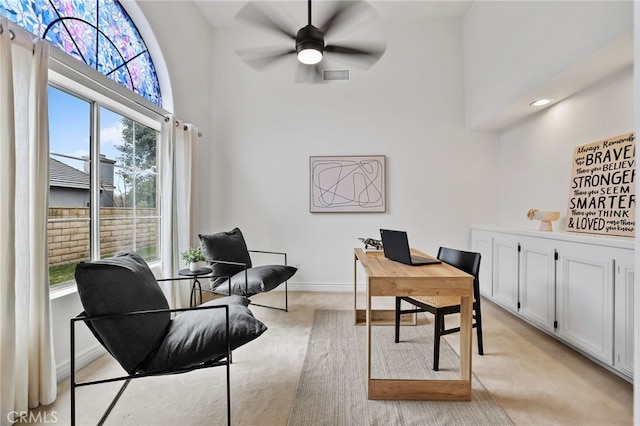 carpeted office featuring a towering ceiling and ceiling fan