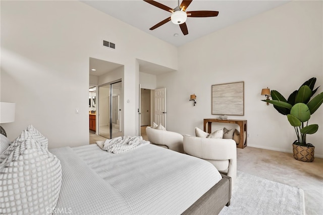 bedroom featuring light carpet, a closet, ceiling fan, and a high ceiling