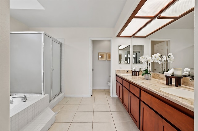 full bathroom with toilet, separate shower and tub, a skylight, vanity, and tile patterned flooring