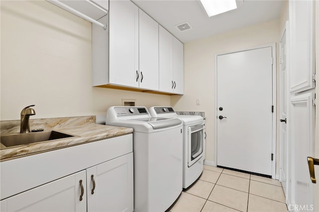 clothes washing area featuring cabinets, sink, washing machine and dryer, and light tile patterned floors