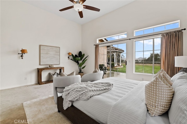 bedroom with light carpet, access to outside, ceiling fan, and a high ceiling