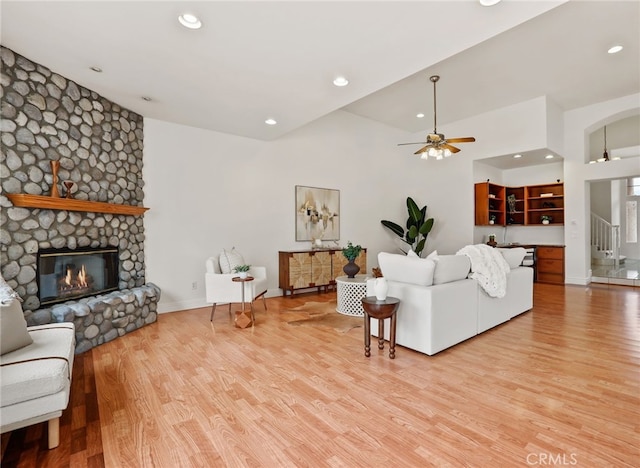 living room featuring ceiling fan, light wood-type flooring, and a fireplace