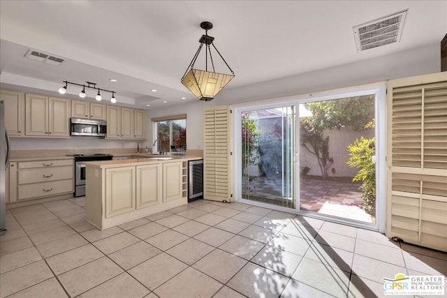 kitchen featuring decorative light fixtures, light tile patterned floors, stainless steel appliances, beverage cooler, and cream cabinets